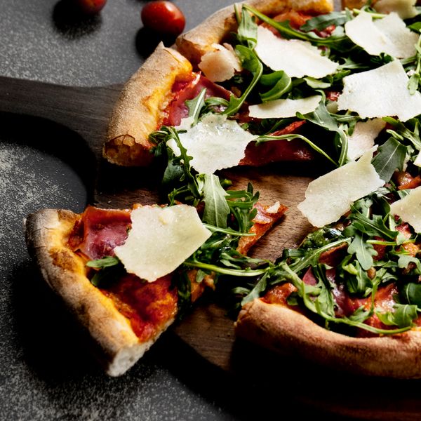 Nahaufnahme einer Pizza mit Parmesan
            und Rucola